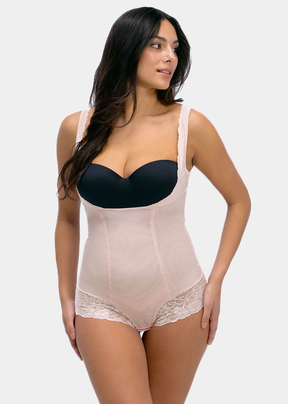 Woman wearing a black strapless top and beige shapewear on a white background