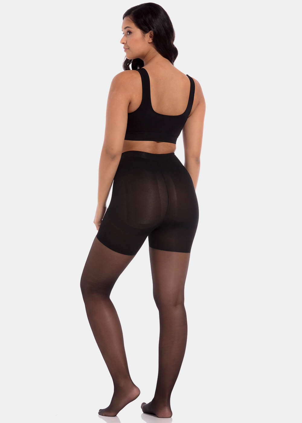 Back view of a model wearing Sexy Legs tights in black, 30 denier shaping tights. Built-in firm shaping shorts providing control for lower back, hips, and upper legs, with subtle lift at the bottom and smooth finish along the legs.