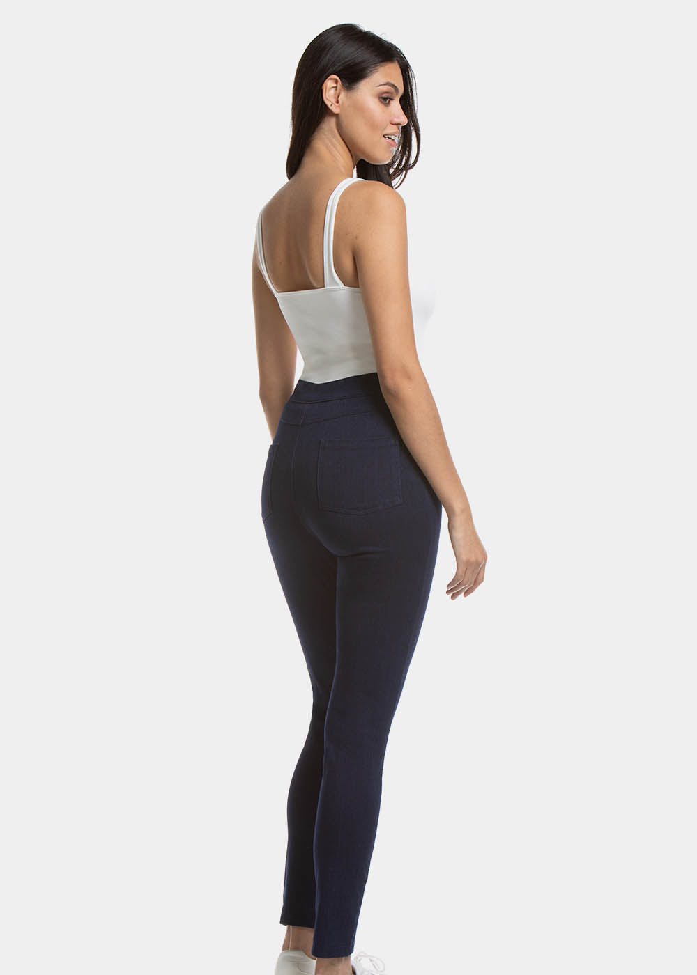 Back view of a model wearing Jegging in blue jeans, high-waist skinny-fit leggings with built-in shaping briefs. Soft stretchy fabric providing medium control for lower back and hips, lifted bottom zone, and functional back pockets visible.