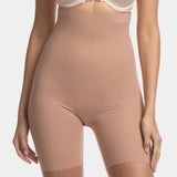 A woman wearing a high-waisted black shapewear Bermuda that extends to mid-thigh.
