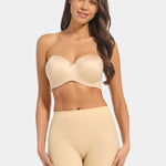 Woman wearing a beige strapless top and high-waisted shorts on a light gray background