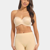 Woman wearing a beige strapless top and high-waisted shorts on a light gray background