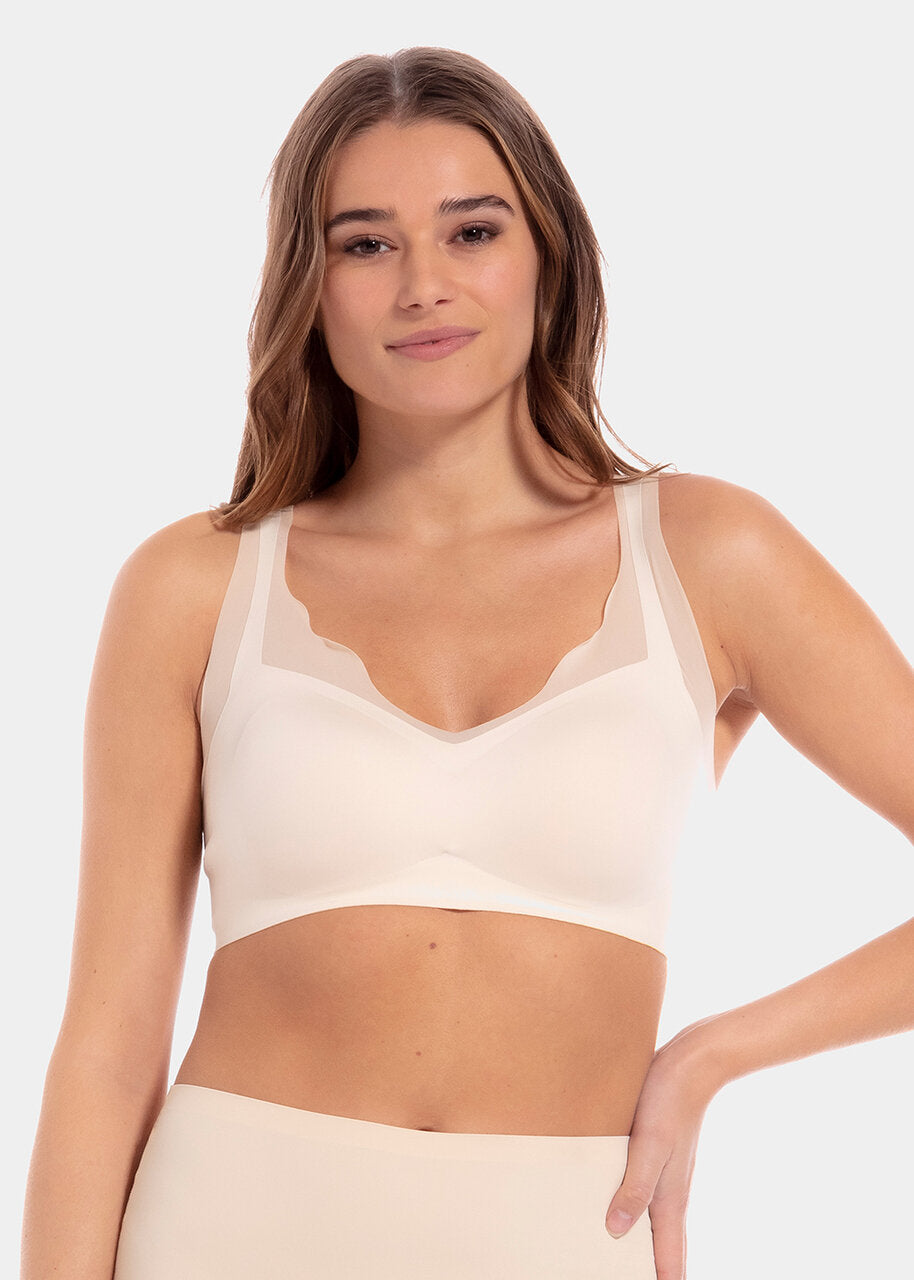 A woman wearing a white Sensual Bra with mesh details at the cups and straps, and a hook-and-eye back closure.