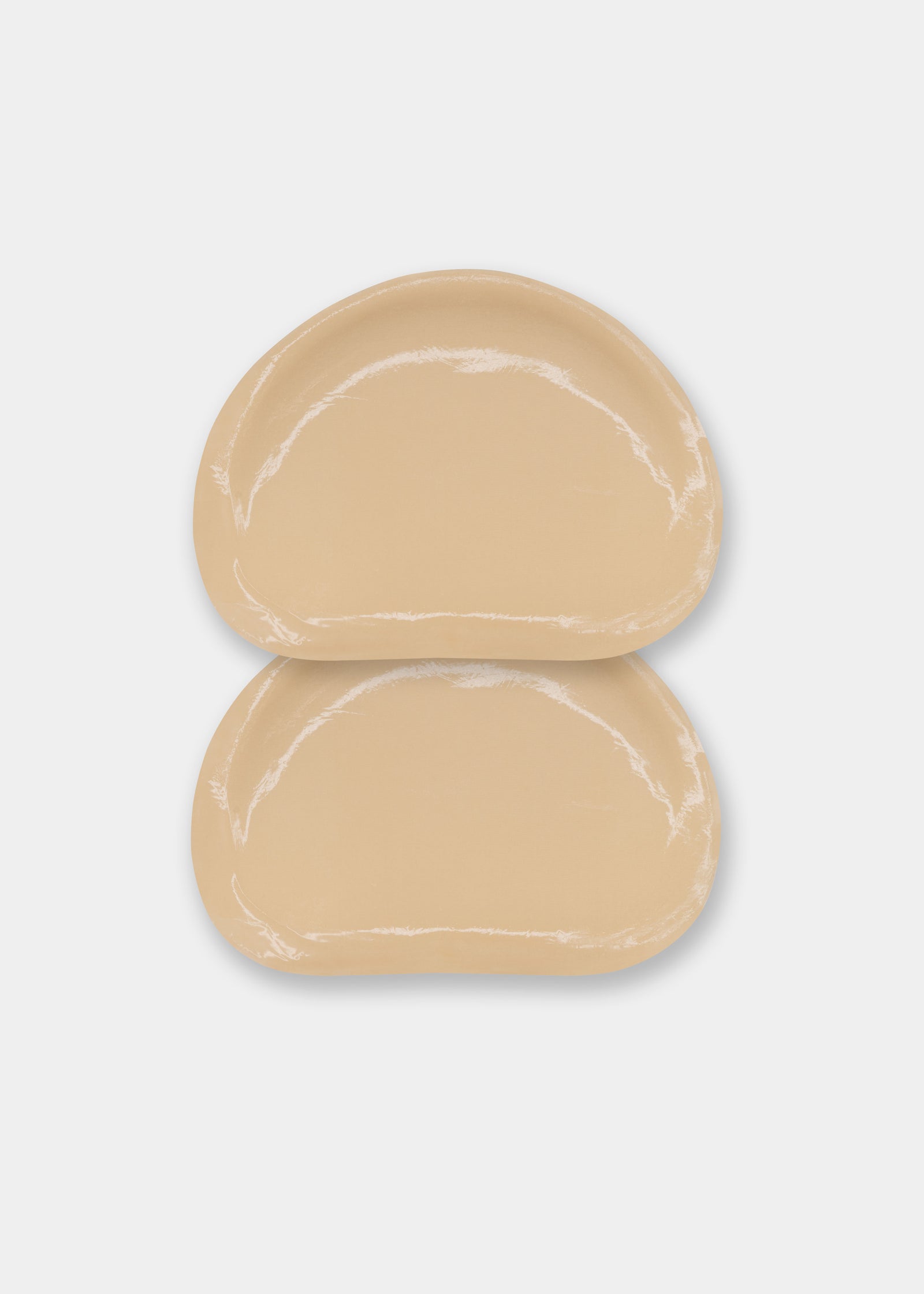 Still product image of Double Sticky Demi Push-Up Pads in latte showing the inside surface. Demi-shaped silicone insert with visible adhesive layer and smooth edges, designed to attach securely inside a bra cup.