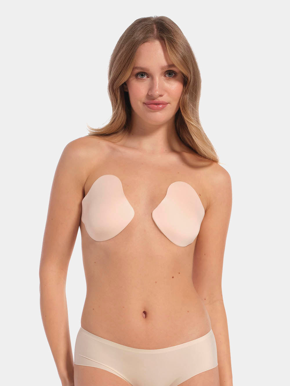 Front view of a model wearing the latte-colored Ultimate Invisibles adhesive bra cups, featuring two separate lightweight cups that create natural cleavage with a smooth, strapless and backless invisible finish.