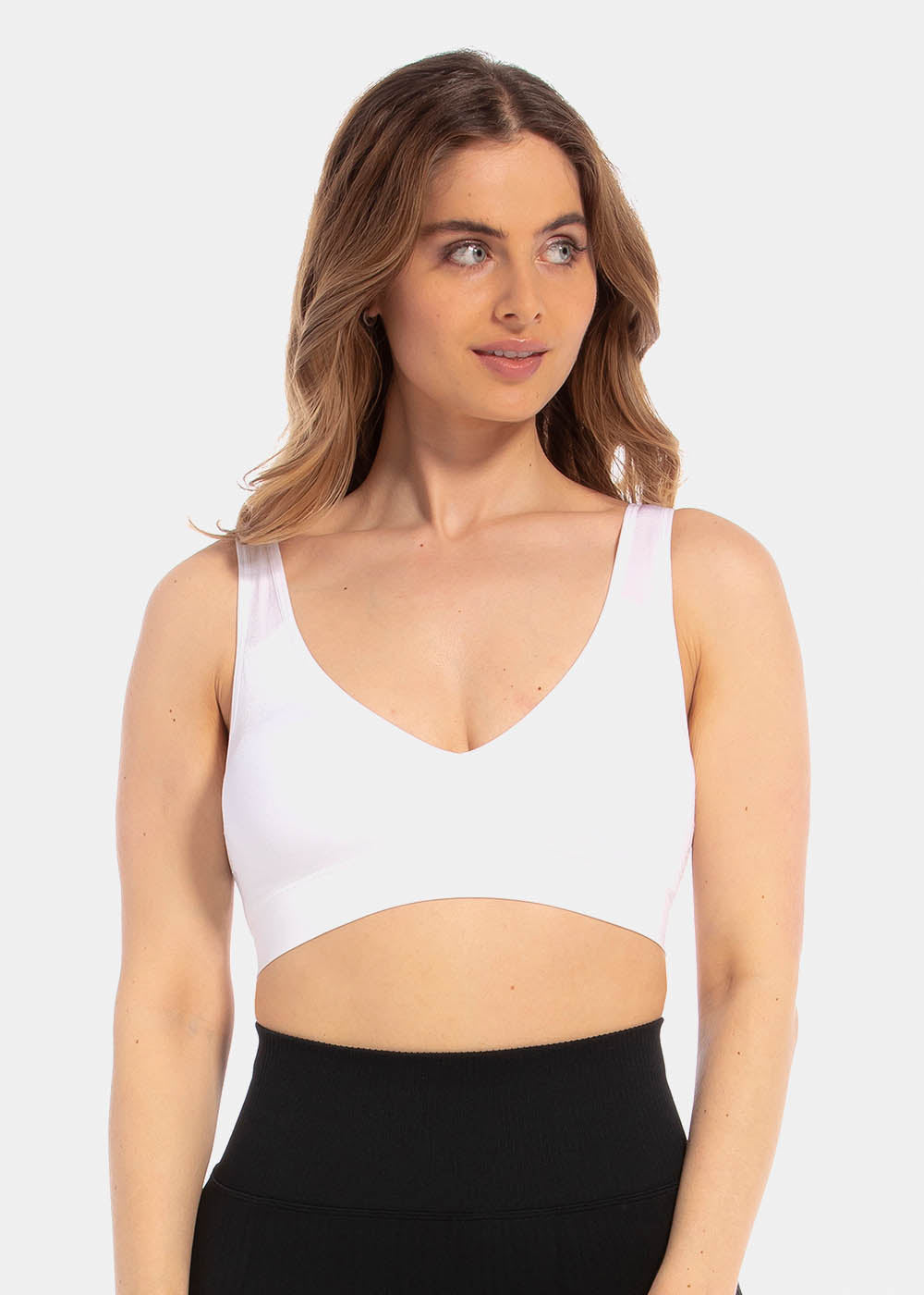 Front view of a model wearing a white Comfort Plunge Bra made from soft, seamless fabric. The wireless bra features a deep V-neckline for a flattering cleavage, wider supportive straps, and a smooth, closure-free back for a clean, comfortable fit.