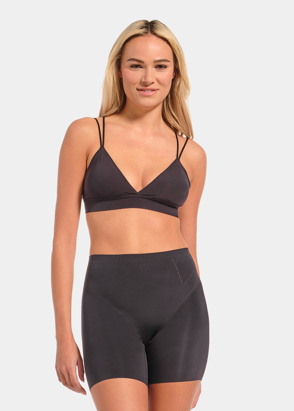 Woman wearing a dark gray sports bra and shorts set on a light gray background
