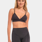 Woman wearing a dark gray sports bra and shorts set on a light gray background