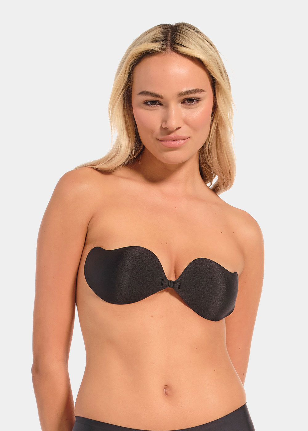 Woman wearing a black strapless bra against a plain background