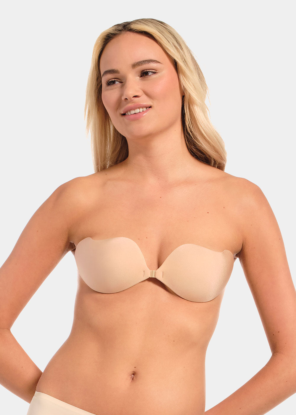Woman wearing a beige strapless bra against a plain background