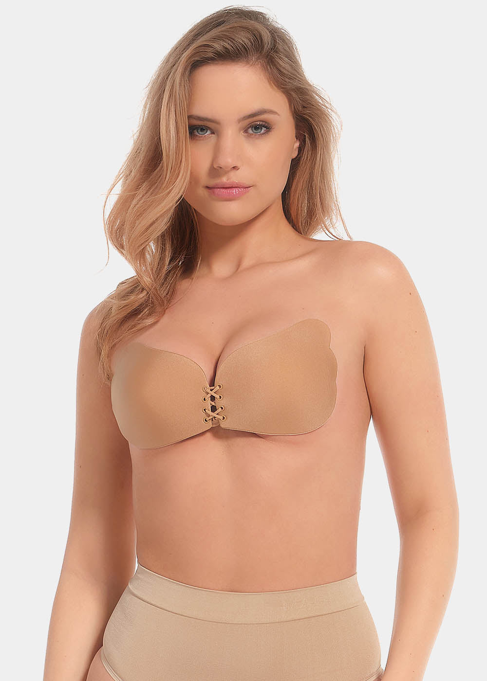 A woman wearing a mocha, backless, strapless adhesive bra with a drawstring front closure.