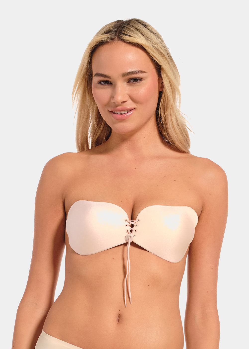 Woman wearing a beige strapless adheasive bra on a white background