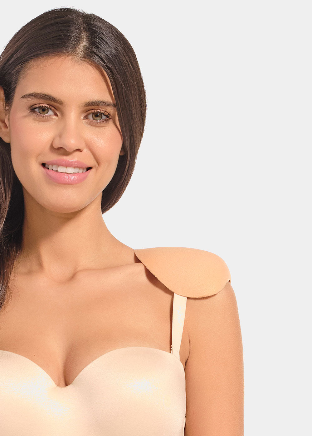 Woman wearing a beige strapless top with shoulderpads against a plain background