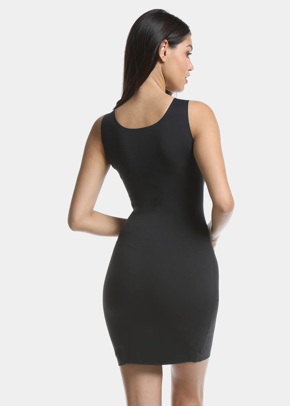 Back view of a model wearing Tone Your Body Dress in black, body-contouring tank dress. Smooth powerful recycled fabric providing firm shaping for back, hips, and legs, with seamless edges, smooth shoulders, and silicone-lined leg openings visible.