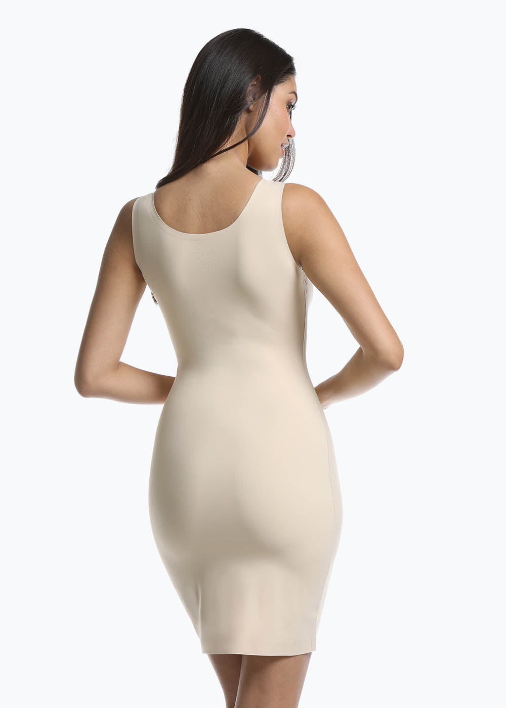 Back view of a model wearing Tone Your Body Dress in latte, body-contouring tank dress. Smooth powerful recycled fabric providing firm shaping for back, hips, and legs, with seamless edges, smooth shoulders, and silicone-lined leg openings visible.