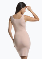 Back view of a model wearing Tone Your Body Dress in cappuccino, body-contouring tank dress. Smooth powerful recycled fabric providing firm shaping for back, hips, and legs, with seamless edges, smooth shoulders, and silicone-lined leg openings visible.