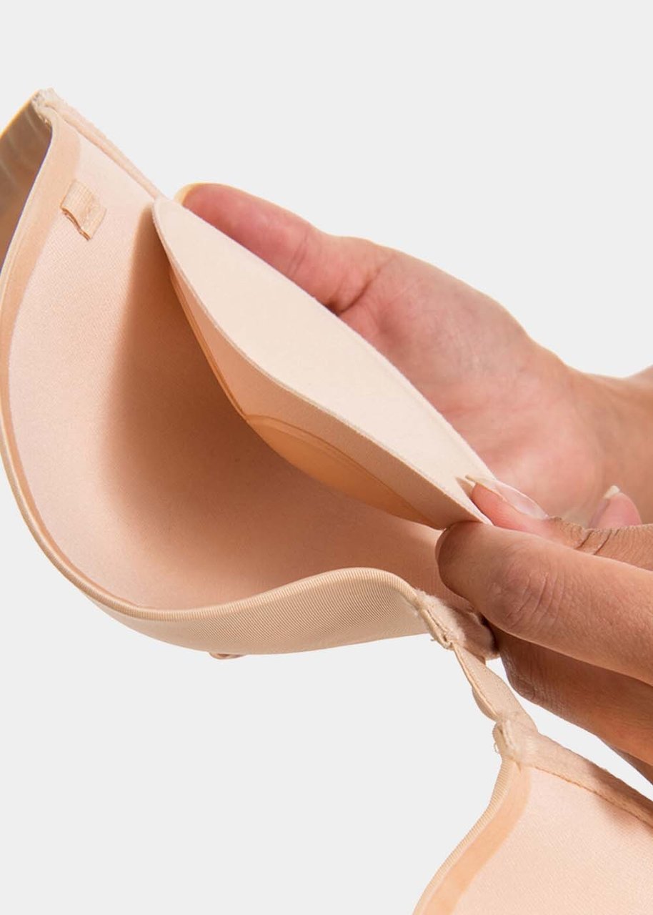 Still product image of Sticky Push-Up Pads in latte shown positioned inside a bra cup. Adhesive insert placed at the lower cup area, with smooth surface and curved shape demonstrating correct placement for lift.