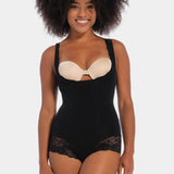 Woman wearing a black bodysuit with a beige bralette on a white background