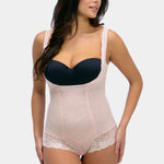 Woman wearing a black strapless top and beige shapewear on a white background