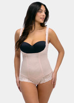 Woman wearing a black strapless top and beige shapewear on a white background