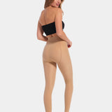 Back view of a model wearing MAGIC Tights in latte, high-waist warm fleece-lined tights. Smooth fabric providing medium shaping for lower back and waist, ladder-resistant finish, and sheer-look legs with unfleece foot section visible.