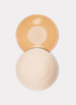 Still product image of the latte-colored MAGIC Hide Your Nipples covers, displayed to show both the front and back, highlighting the soft fabric outer surface and the inner adhesive layer with a comfort-focused center.