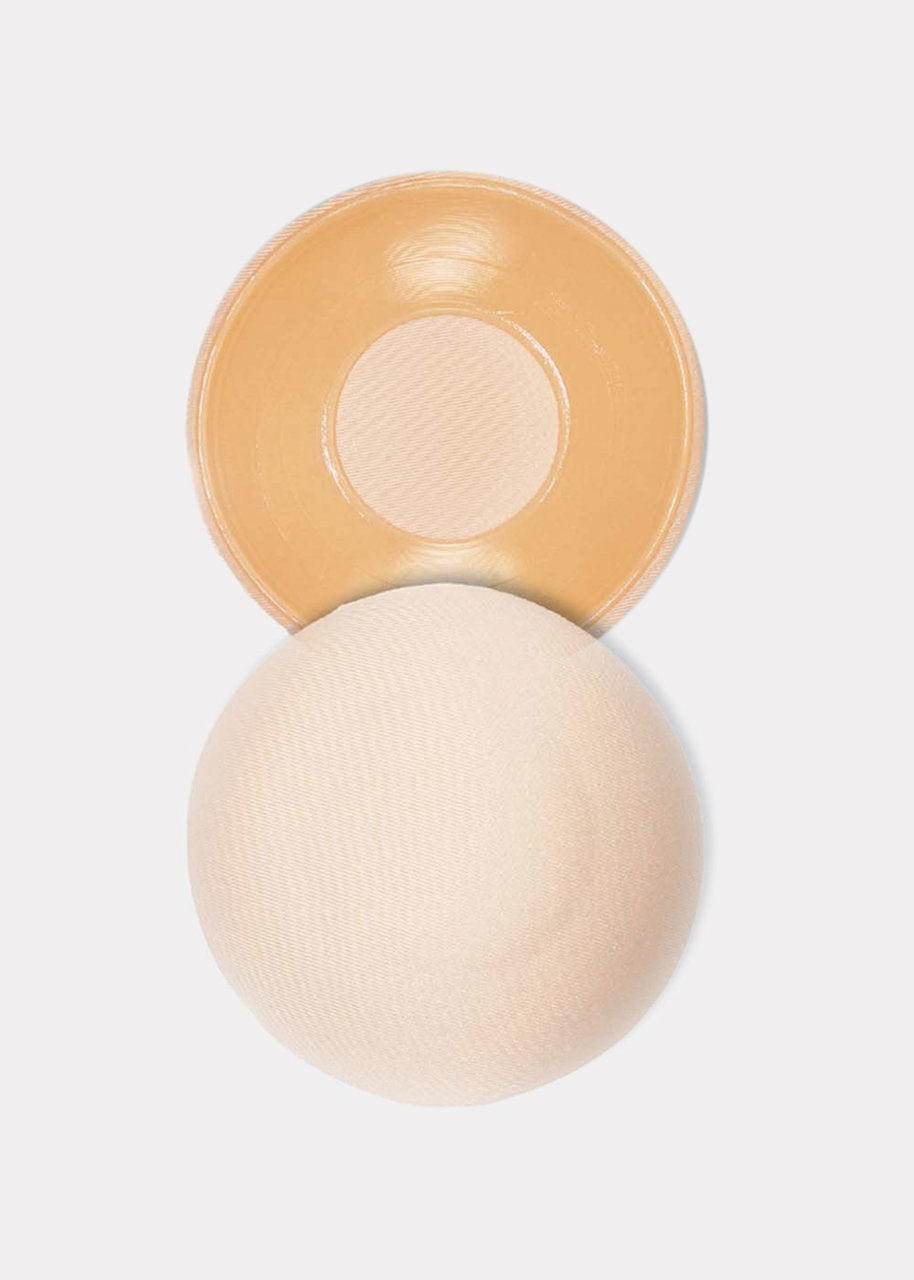 Still product image of the latte-colored MAGIC Hide Your Nipples covers, displayed to show both the front and back, highlighting the soft fabric outer surface and the inner adhesive layer with a comfort-focused center.