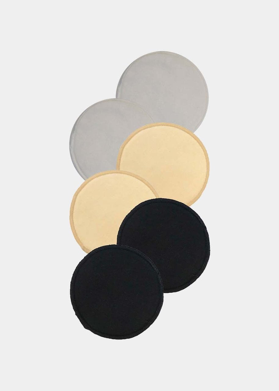 Still product image of Nursing Pads in black, latte, and white. Round absorbent pads made of bamboo and cotton fibers, shown flat with smooth fabric surface and stitched edges.