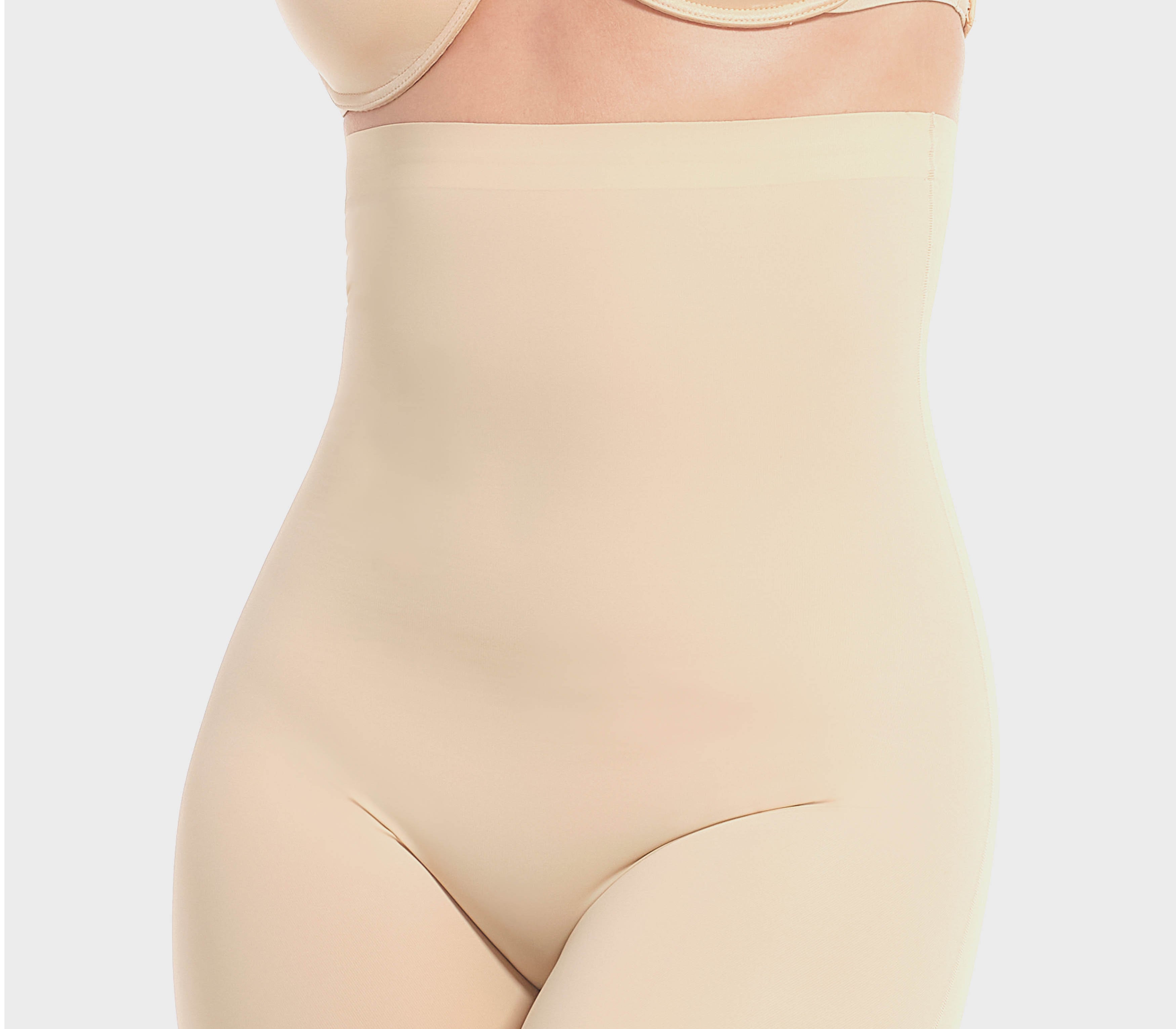 A woman wearing a high-waisted black shapewear Bermuda that extends to mid-thigh.