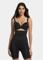 A woman wearing a high-waisted black shapewear Bermuda that extends to mid-thigh.