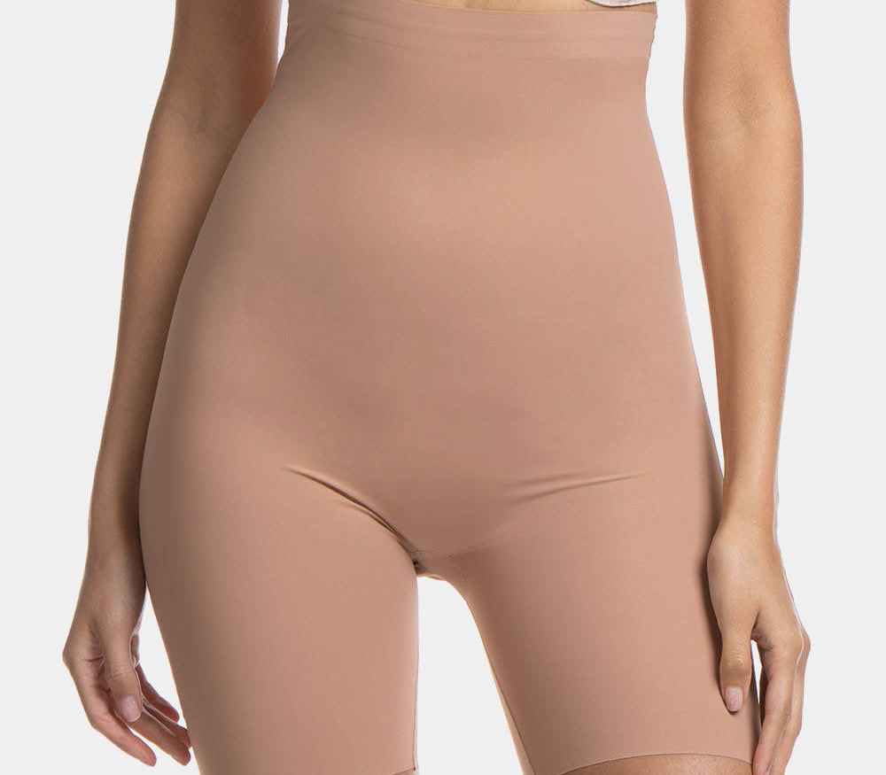 A woman wearing a high-waisted black shapewear Bermuda that extends to mid-thigh.