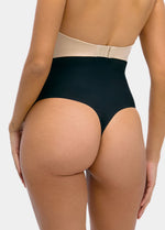 Person wearing black high-waisted thong with beige waistband on a plain background