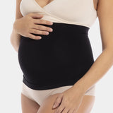 Front view close-up of a pregnant model wearing Mama Supporting Belly Band in black, seamless maternity band. Soft stretchable fabric with under-bump support panel and silicone trim at top and bottom visible, showing smooth fit over the belly.