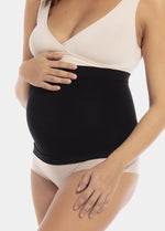 Front view close-up of a pregnant model wearing Mama Supporting Belly Band in black, seamless maternity band. Soft stretchable fabric with under-bump support panel and silicone trim at top and bottom visible, showing smooth fit over the belly.