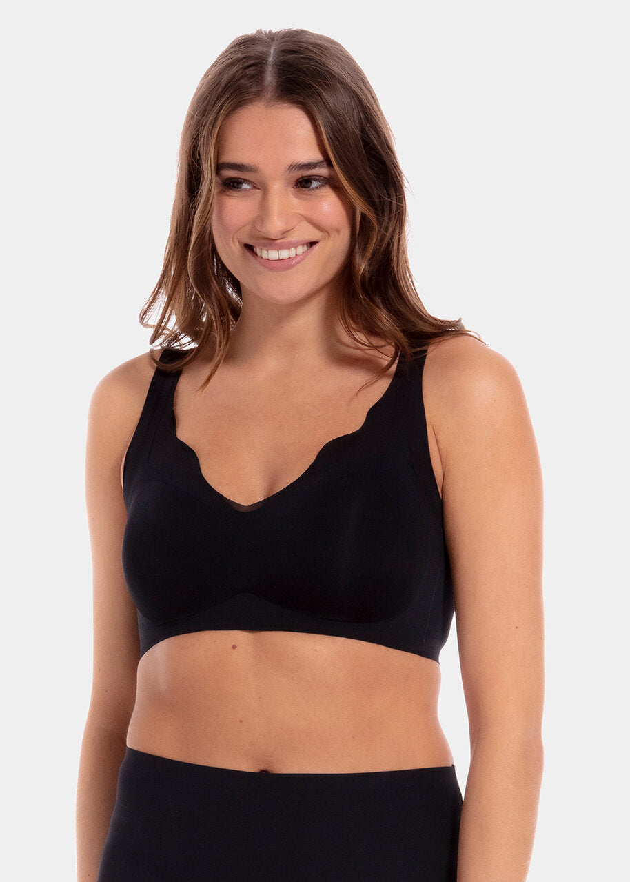 A woman wearing a black Sensual Bra with mesh details at the cups and straps, and a hook-and-eye back closure.