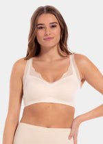 A woman wearing a white Sensual Bra with mesh details at the cups and straps, and a hook-and-eye back closure.