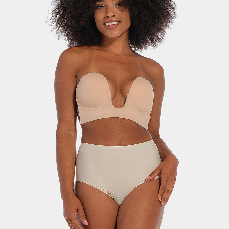 A woman wearing a cappuccino strapless, backless, and adhesive bra with a low U-plunge neckline.