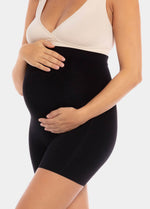 Front view of a model wearing Mama Supporting Short in black, over-the-bump seamless maternity shapewear shorts. Smooth stretchable fabric with mid-thigh length and supportive belly panel, designed for support and invisible wear under clothing.