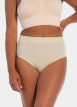 Front view of a model wearing the Comfort Thong, showcasing the soft, seamless fabric with light shaping through the lower tummy and a smooth, invisible finish under clothing.