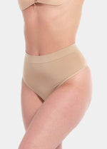 Front view of a model wearing the cappuccino-colored Comfort Thong, featuring soft, seamless fabric with light shaping support and a smooth, invisible finish under clothing.