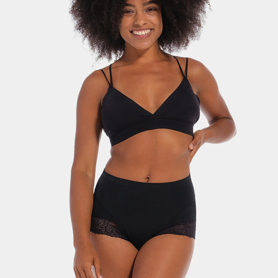 Black mid-waist shaping brief worn by a model in a front-facing standing position, featuring firm lower tummy and back shaping with built-in powernet support, smooth strong breathable fabric, flat invisible lace, and cotton gusset lining.