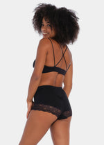 Black mid-waist shaping brief worn by a model in a back-facing standing position, featuring firm shaping with built-in powernet support, smooth strong breathable fabric, and flat invisible lace for a seamless sculpting fit.