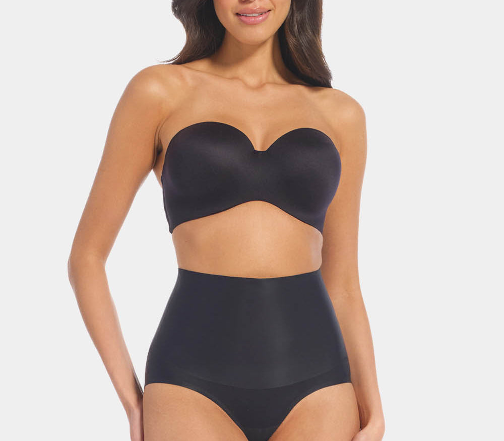 Front view of a model wearing Tummy Shaper in black, mid-waist shaping brief with double-layer waistband. Seamless design with smooth fabric and full front coverage, providing firm shaping at the tummy area.