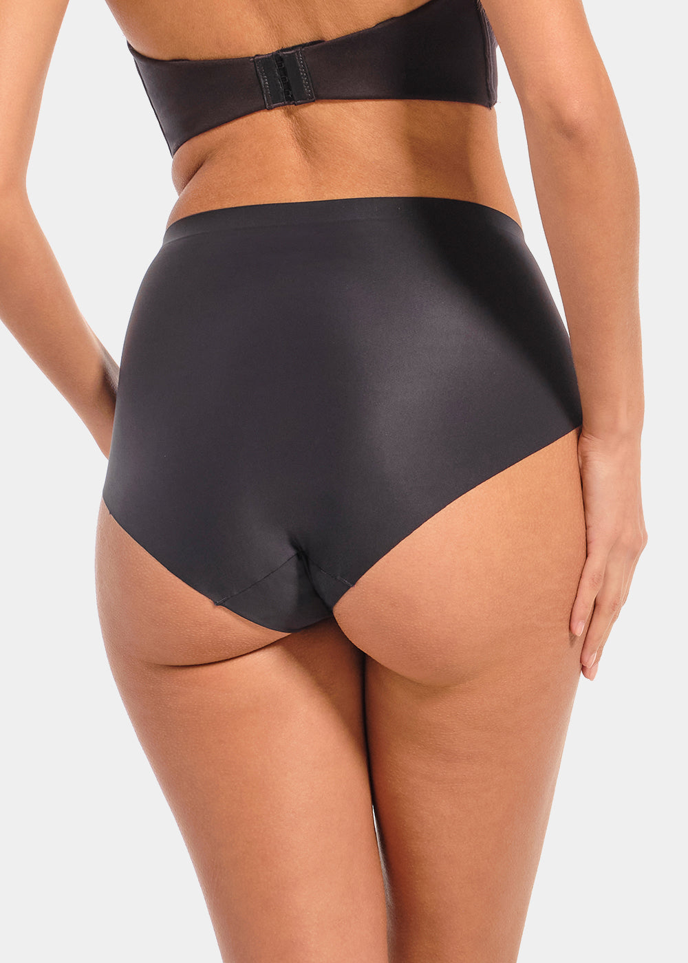 Back view of a model wearing Everyday Shaper Brief in black, mid-waisted seamless shapewear brief. Smooth, lightweight fabric with full back coverage and seamless edges, designed for invisible shaping under clothing.