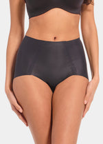 Front view of a model wearing Everyday Shaper Shorty in black, mid-waisted seamless shapewear shorts. Cropped image showing waistband and upper thigh area, with smooth fabric and seamless finish for invisible shaping under clothing.