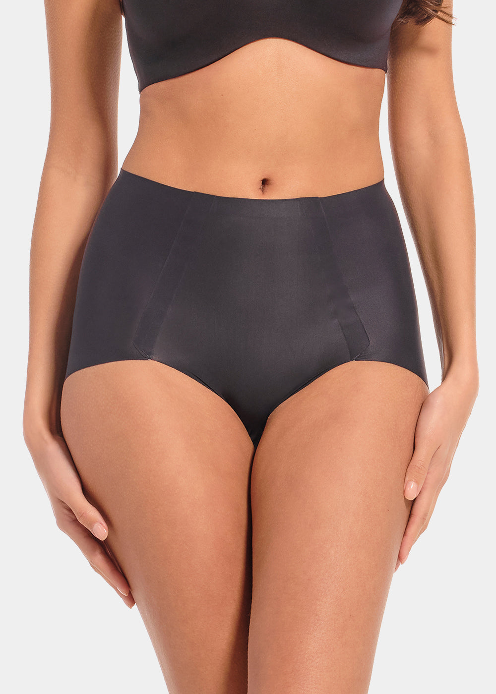 Front view of a model wearing Everyday Shaper Shorty in black, mid-waisted seamless shapewear shorts. Cropped image showing waistband and upper thigh area, with smooth fabric and seamless finish for invisible shaping under clothing.