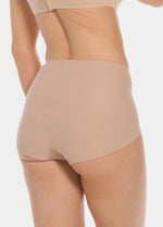 Back view of a model wearing Everyday Shaper Shorty in cappuccino, mid-waisted seamless shapewear shorts. Smooth fabric with short legs and seamless edges, providing invisible coverage across the back and upper thighs.