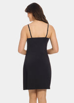 Back view of a model wearing Everyday Underdress in black, lightweight underdress with adjustable straps. Relaxed fit with smooth, flowy fabric and mid-thigh length, showing straight back design for invisible layering under clothing.