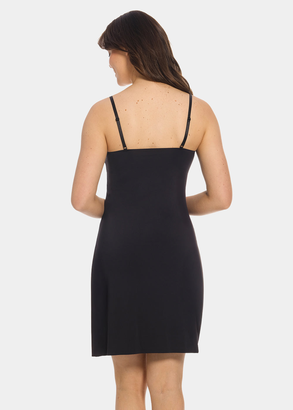 Back view of a model wearing Everyday Underdress in black, lightweight underdress with adjustable straps. Relaxed fit with smooth, flowy fabric and mid-thigh length, showing straight back design for invisible layering under clothing.