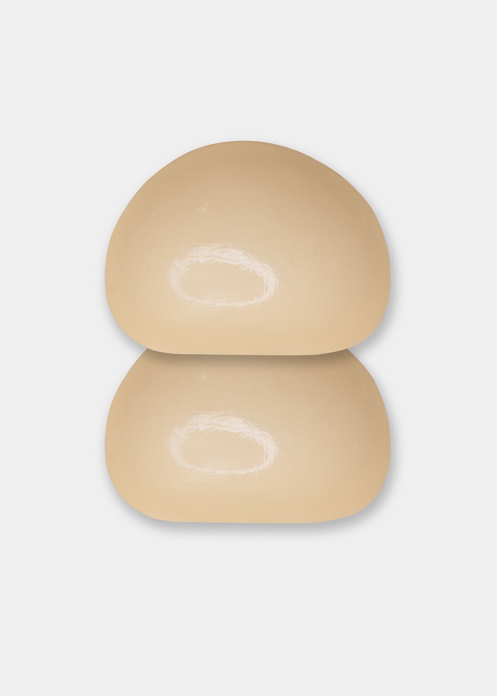 A beige-colored demi push-up pad with adhesive on both the inside and outside, designed for discreet lift and stay-put fit.